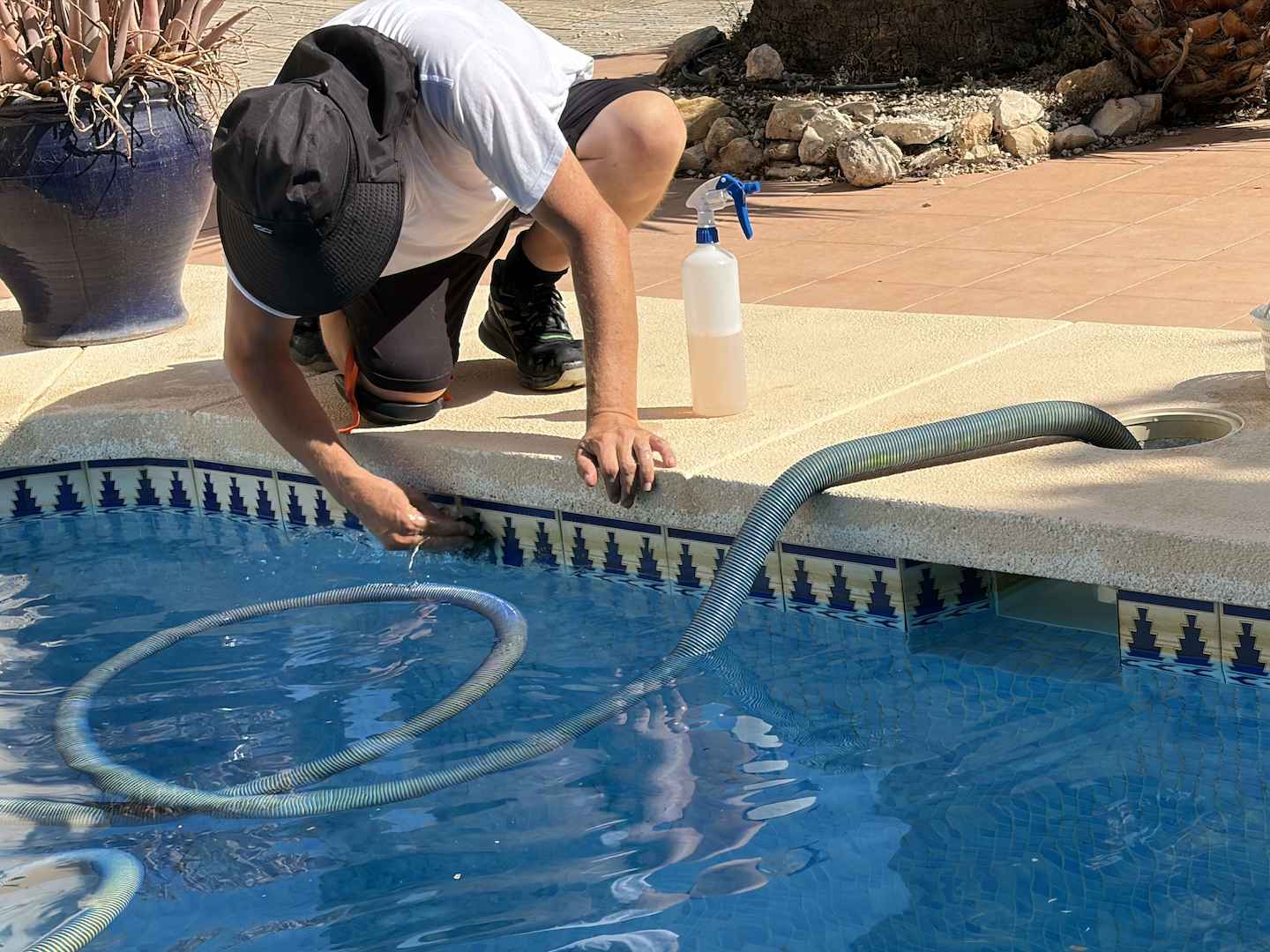 Pool technician carrying out detailed cleaning of the waterline in a private swimming pool