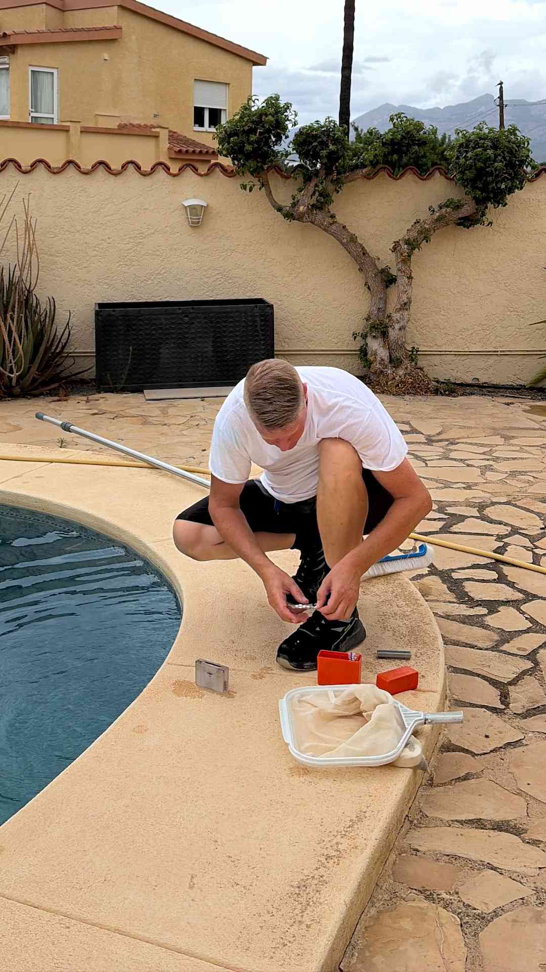 Pool technician carrying out detailed cleaning of the waterline in a private swimming pool